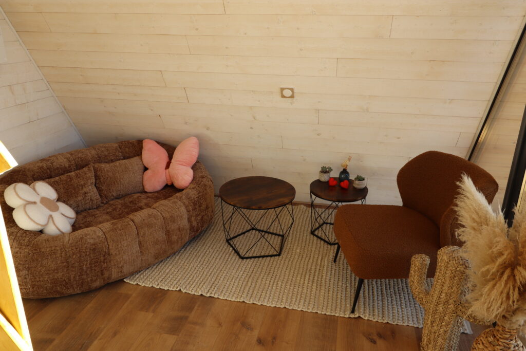 Salon cosy de la cabane en A L'Amoré avec canapé rond, fauteuils et ambiance romantique en Occitanie
