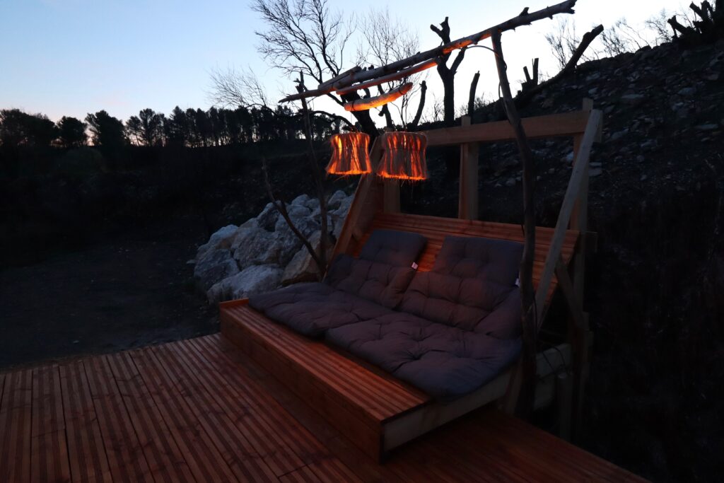 Coin détente extérieur en bois avec éclairage chaleureux pour soirée romantique à deux à L'Amoré en Occitanie