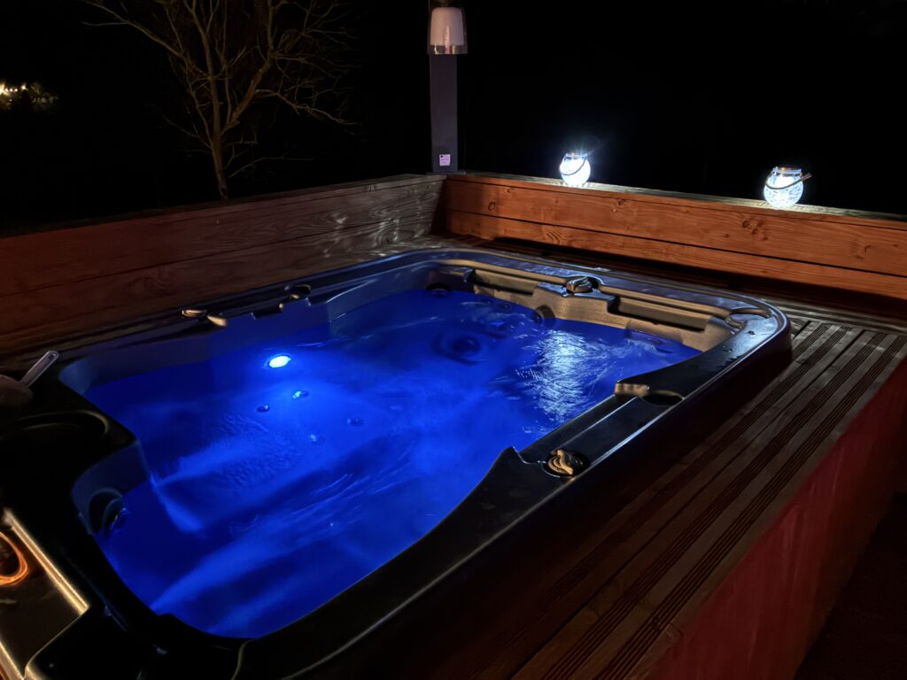 Jacuzzi privatif extérieur chauffé sous le ciel étoilé des Corbières, ambiance romantique avec éclairage tamisé pour un séjour en amoureux dans l'Aude.
